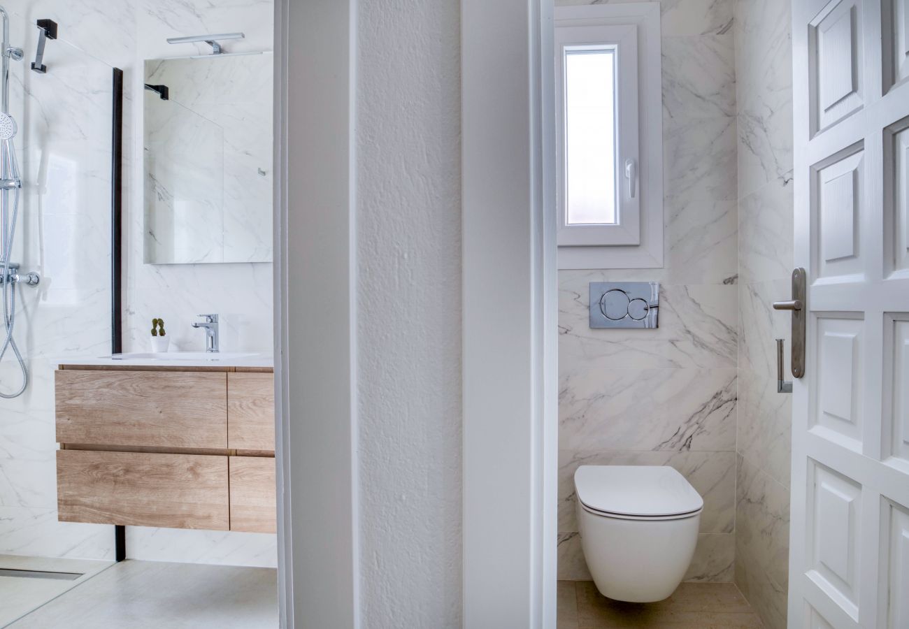 Salle de bain lumineuse avec toilettes séparées.